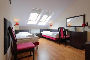 a bedroom with two beds and a desk and chairs at Dworek Różany Hotel & Restauracja in Namysłów