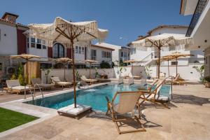a pool with chairs and tables and umbrellas at Armel Alaçatı in Alacati