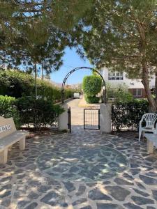 un parque con una puerta, bancos y un árbol en Apartment with Outdoor Pool and Air Conditioning in Cabo Roig, en Cabo Roig