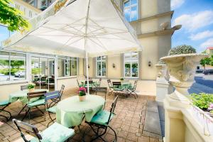 eine Terrasse mit Tischen, Stühlen und einem Sonnenschirm in der Unterkunft Hotel Kaiserin Augusta in Weimar