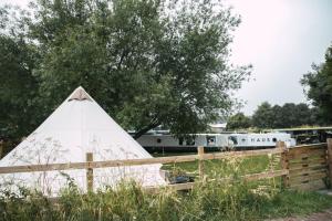 a teepee leaning against a fence with a train in the background at Stoffhaus in Skipton