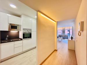 a kitchen with white cabinets and a living room at Apartamento Rambla Vella in Tarragona