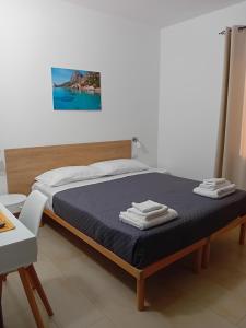 a bedroom with a bed with a blue blanket and a table at Eliseo's rooms in Triei