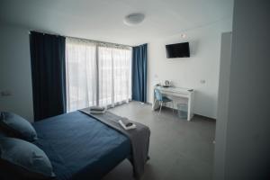 a bedroom with a bed and a desk and a television at Al Vicolo Comfort Room in SantʼAgata di Militello