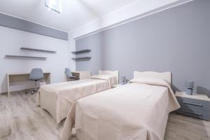 a white room with three beds and a desk at Damilhouse 3 in Messina