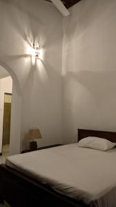 1 dormitorio con 1 cama y una luz en la pared en Verandas Trincomalee, en Trincomalee