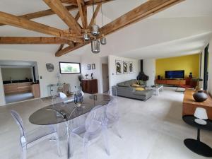 ein Wohnzimmer mit einem Glastisch und Stühlen in der Unterkunft villa avec studio indépendant et piscine in Jonquières