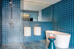 a blue tiled bathroom with a tub and a sink at Maison Arya in Brussels