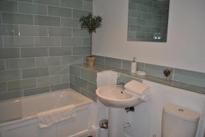a bathroom with a sink and a tub and a toilet at Two Bedroom Windsor Flats with Parking in Windsor