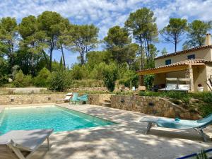 a swimming pool with two chairs and a house at Mas provençal in Draguignan