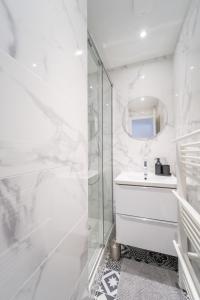 een witte badkamer met een douche en een wastafel bij Appart' Terrasse plein centre in La Ferté-Gaucher