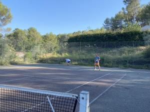 two people playing tennis on a tennis court at Mas provençal in Draguignan