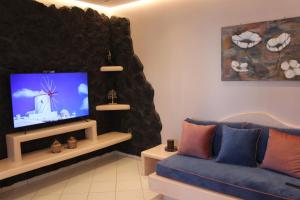 Il comprend un salon doté d'un canapé bleu et d'une télévision à écran plat. dans l'établissement THE ROCK LUXURY HOMES, à Mesariá