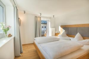 a white bedroom with a large bed and a window at Landhaus Ohrwumslar in Oberstdorf
