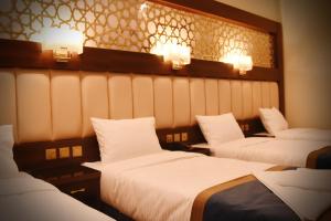 a room with three beds with lights on the wall at فندق الاندلس الماسى in Al Madinah