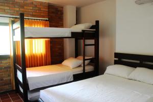 Pokój z 3 łóżkami piętrowymi i ceglaną ścianą w obiekcie Hotel San Marcos Taganga w mieście Taganga