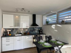 a kitchen with white cabinets and a table with chairs at Ferienwohnung Zur alten Dorfschule in Lünebach