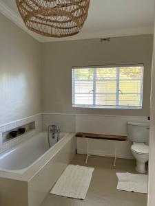 baño con bañera, aseo y ventana en Hartebeeskraal Selfcatering cottage, en Paarl