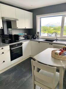 cocina con armarios blancos, mesa y ventana en Bryn Mair cottage overlooking Snowdon en Caernarfon