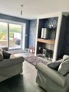 a living room with a couch and a television at Bryn Mair cottage overlooking Snowdon in Caernarfon