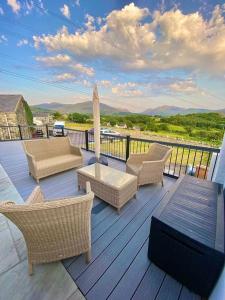 a deck with wicker chairs and a table on a balcony at Bryn Mair cottage overlooking Snowdon in Caernarfon