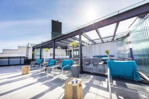a patio with blue chairs and tables on a roof at Hotel Klaus K in Helsinki