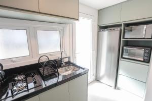 a kitchen with a sink and a refrigerator at Sobrado Aconchegante em Canela 114 in Canela