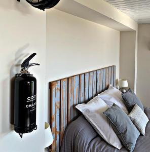ein Schlafzimmer mit einem Bett mit einem schwarzen Gaszylinder an der Wand in der Unterkunft Les gîtes du Canal du midi - Gîte Bois & Cailloux in Montgaillard-Lauragais