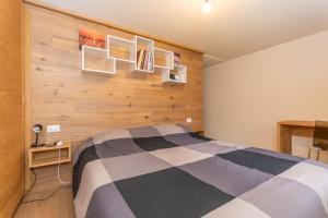 ein Schlafzimmer mit einem Bett und einer Holzwand in der Unterkunft Appartamenti Marangon in Falcade