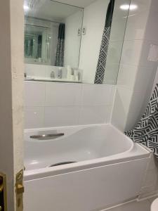 een witte badkamer met een bad en een spiegel bij Charming 2-Bed House in London in Londen