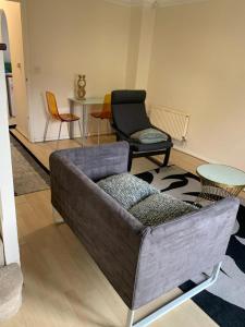 een woonkamer met een bank, stoelen en een tafel bij Charming 2-Bed House in London in Londen