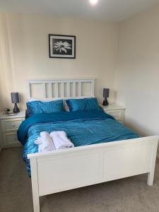 a white bed with blue sheets and towels on it at Charming 2-Bed House in London in London