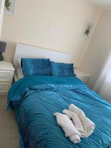 a blue bed with two white towels on it at Charming 2-Bed House in London in London