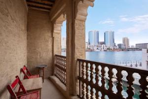 two red chairs sitting on a balcony overlooking the water at Al Seef Heritage Hotel Dubai, Curio Collection by Hilton in Dubai