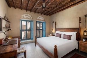 a bedroom with a bed and a desk and windows at Al Seef Heritage Hotel Dubai, Curio Collection by Hilton in Dubai