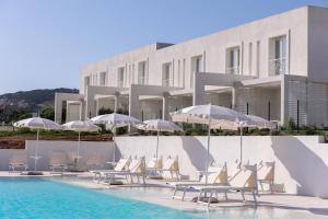 un hôtel avec des chaises et des parasols à côté d'une piscine dans l'établissement Stunning Capo Falcone Charming Apartments 1 Bedroom Apt sleeps 4, à Stintino