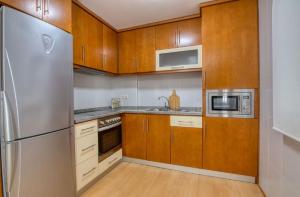 uma cozinha com armários de madeira e um frigorífico de aço inoxidável em O Aserradero em Finisterre