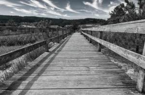 un puente de madera sobre un campo con cielo en O Aserradero, en Finisterre