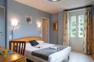 Schlafzimmer mit einem Bett, einem Tisch und einem Fenster in der Unterkunft Logis Hôtel La crémaillère in Hagetmau