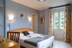 a bedroom with a bed and a table and a window at Logis Hôtel La crémaillère in Hagetmau