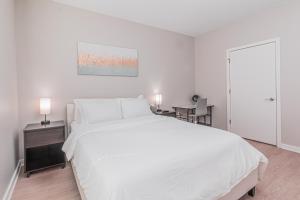 a white bedroom with a large bed and a desk at Luxury Living City Views DC in Arlington