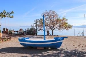 East & West Seaside Apartments في Gialtra: مركب ازرق جالس على الارض بجانب الماء