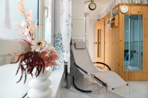a room with a chair and a vase with flowers at Spawo mit Sauna und Whirpool in Pfullendorf