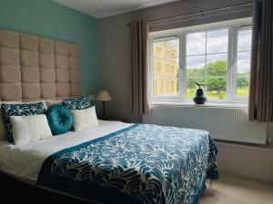 sypialnia z łóżkiem z niebieską kołdrą i oknem w obiekcie The Garden Suite at Shuttleworth w mieście Old Warden