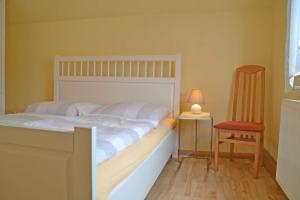 a bedroom with a large white bed and a chair at Pension Pusch Inh_ Ursula Pusch in Guben