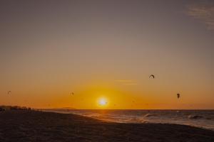 un grupo de personas volando cometas en la playa al atardecer en Ventana Hotel en Prea