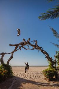 Um homem está a lançar um papagaio na praia. em Ventana Hotel em Praia do Preá