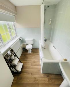 a bathroom with a tub and a toilet and a sink at The Garden Suite at Shuttleworth in Old Warden