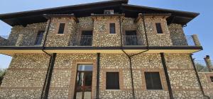 - un bâtiment en pierre avec un balcon au-dessus dans l'établissement Borgo Caridà - Green Family Holidays, à Zaccanopoli