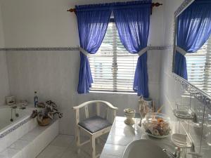 Un baño con cortinas azules y un lavabo y una silla. en Ou Klipskuur Self-Catering Accommodation, en Fraserburg 49 fotos más